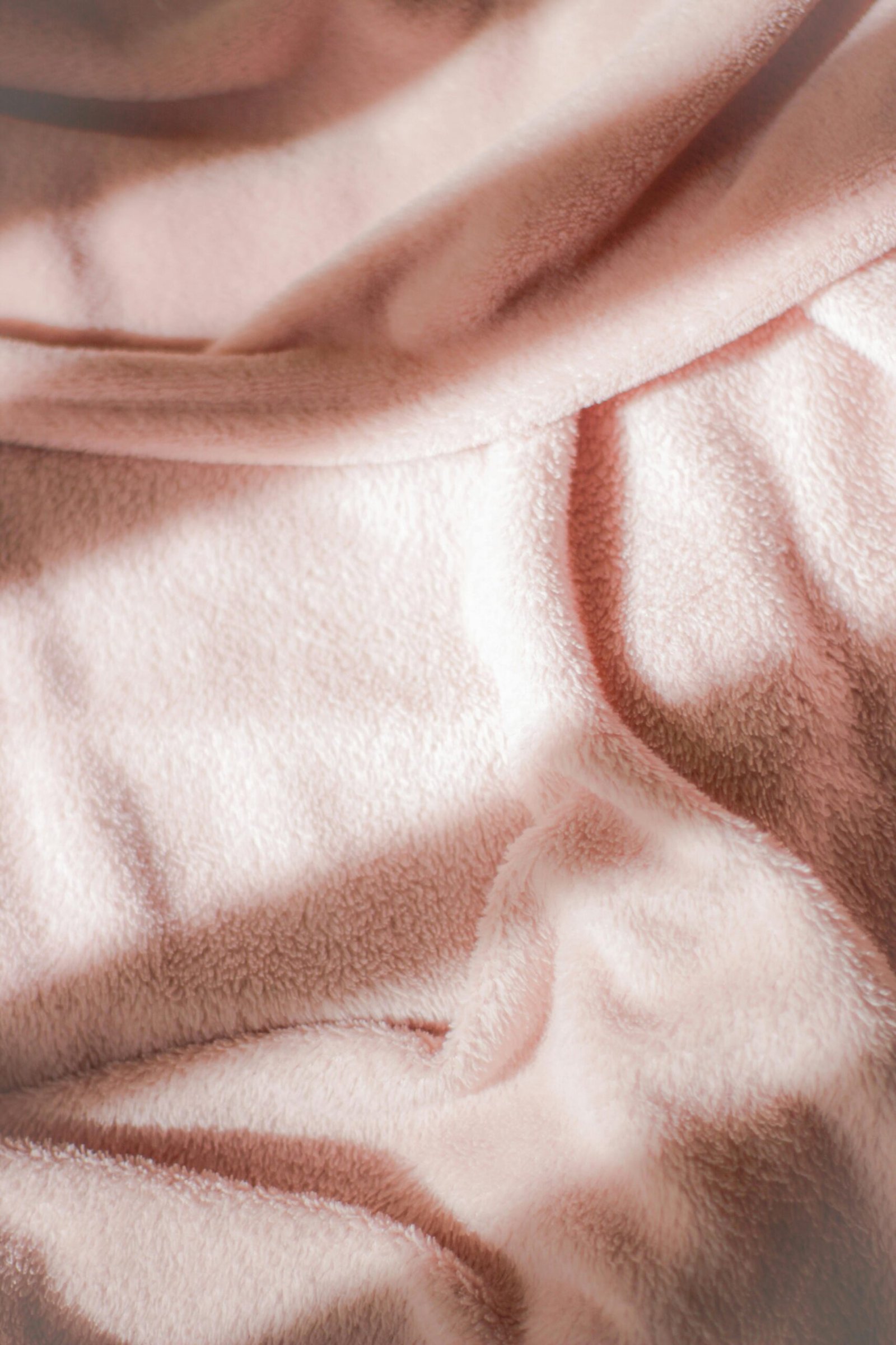 Close-up of a soft pink velvet fabric with rippled texture, perfect for textile and design themes.