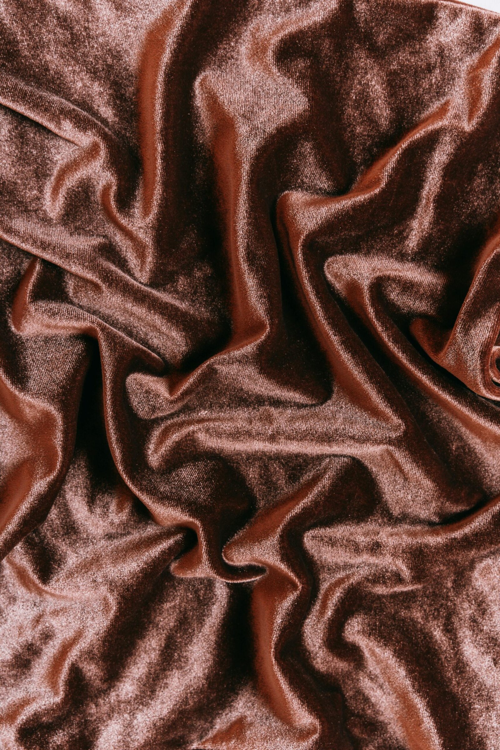 Close-up of luxurious red velvet fabric with a shiny, creased texture, perfect for design and fashion concepts.